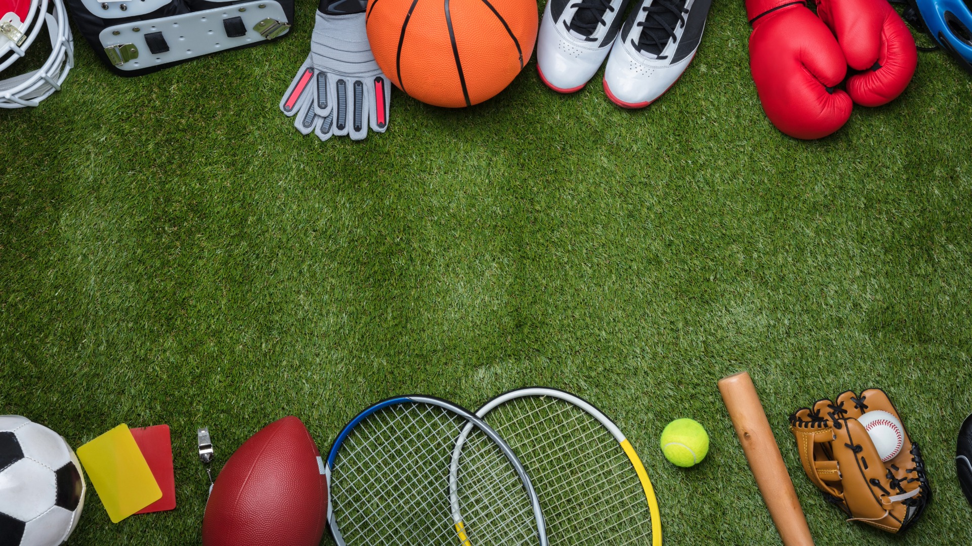 Verschiedene Sportgeräte wie Fußball, Rugbyball, Tennisschläger, Basketball, Baseballhandschuh, Boxhandschuhe und Torwartausrüstung auf grünem Rasen