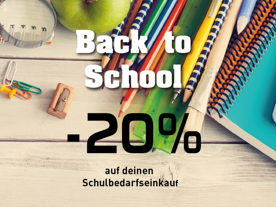 Bunte Schulutensilien mit Buntstiften, Lineal, Heften, Pinsel, Spitzer und Büroklammern auf einem hellen Holztisch.